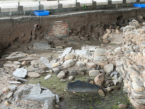 卑南遺址公園的現地考古探坑（考古現場），考古探坑中鋪石地面與陶片的泥土層中，留有一段現代的水管的遺跡。